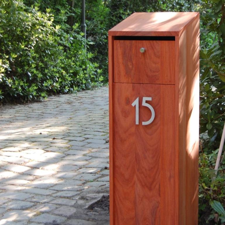 Une boîte aux lettres en bois sur pied avec un numéro de maison