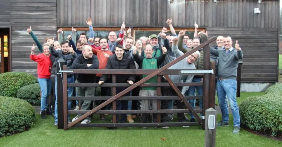 Un groupe de personnes âgées devant une barrière de champ en bois avec un sommet arqué.